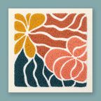 Punch needle wall art kit featuring a sunflower, rose bloom, and teal leaves in mustard yellow, terracotta, and dusty rose