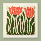 Punch needle wall art with two coral-pink tulips, forest green stems, and warm cream background in bold folk-art style
