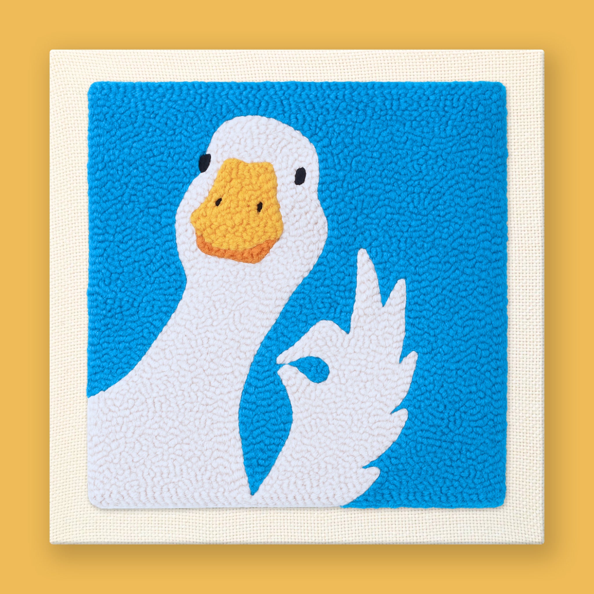 Cute white duck punch needle art making an OK hand gesture with its wing on bright blue background
