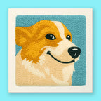 Punch needle wall art of a smiling golden corgi dog on turquoise background in a white frame